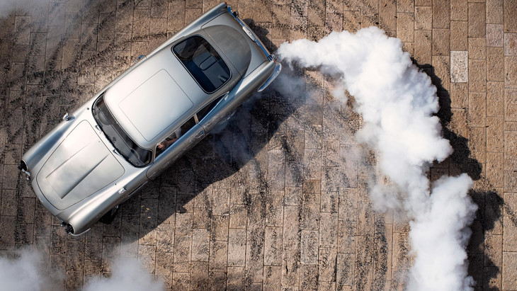 View from above as a spinning silver car leaves a trail of smoke 