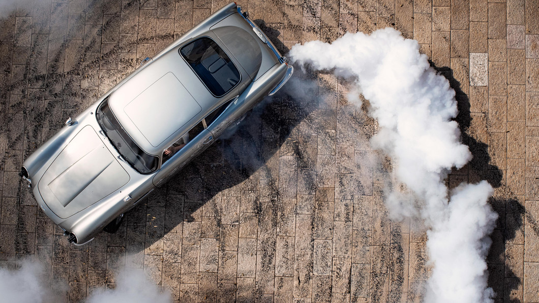 View from above as a spinning silver car leaves a trail of smoke 