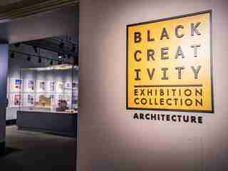 The exhibit entrance with a yellow sign saying Black Creativity Exhibition Collection Architecture