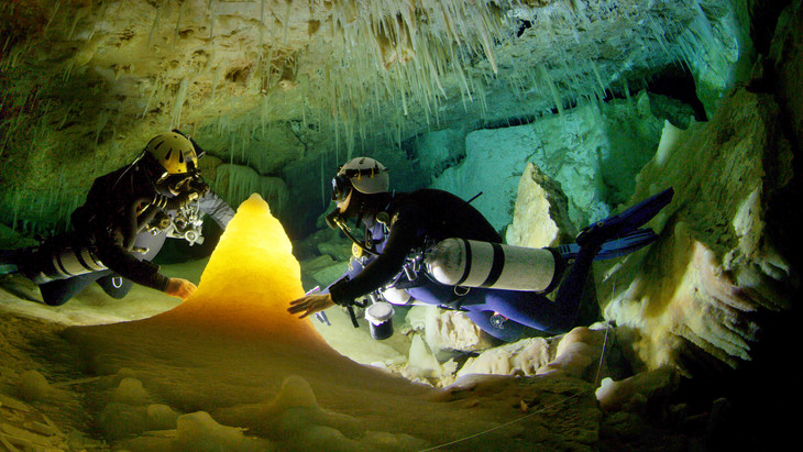 Divers look at a formation in an underwater cave