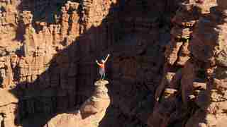 A person stands on top of a narrow rock formation in Moab