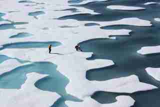 An overhead image of Arctic Sea ice as a Coast Guard crew retrieves a canister of supplies dropped by air.